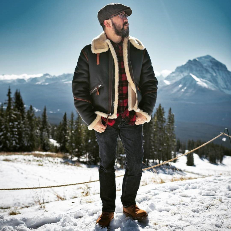 are leather jackets good for winter? Man in fur lined leather jacket stood on snow covered ski slope